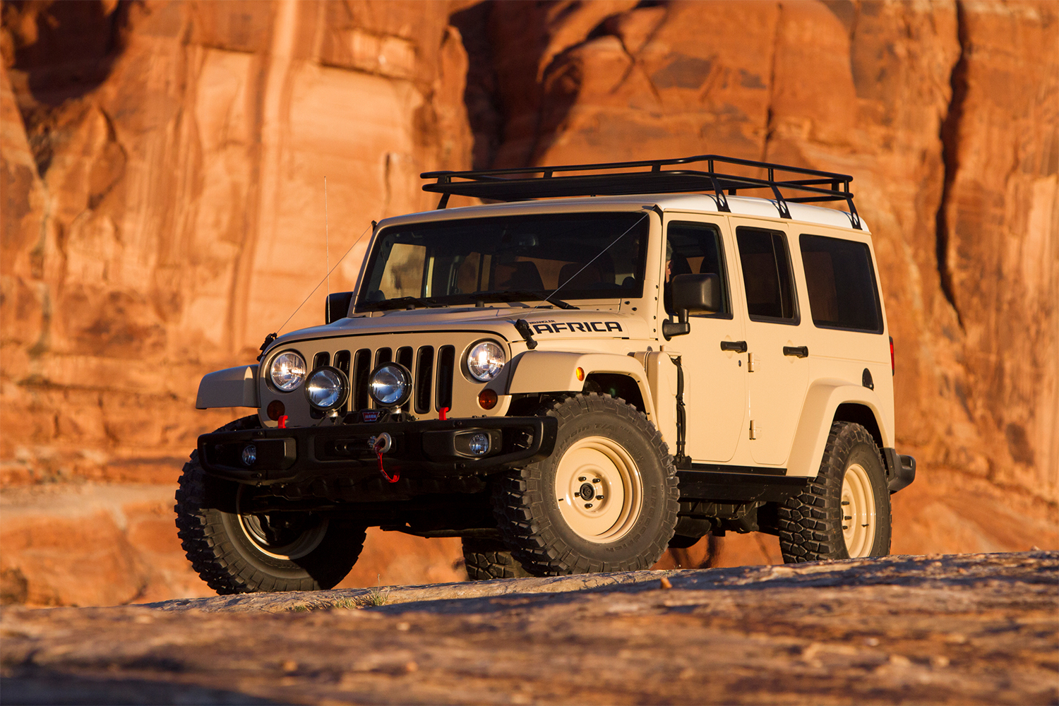 A tan Jeep Wrangler sitting on a cliff in Moab at the Easter Jeep Safari