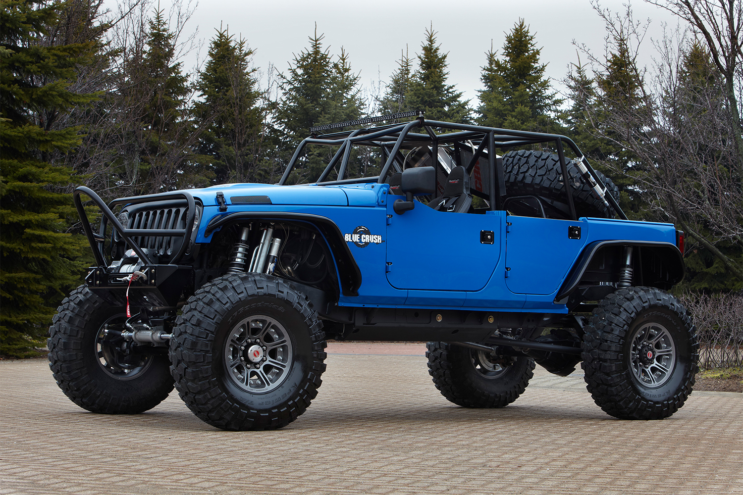 A blue Jeep Wrangler with a suspension lift and no roof