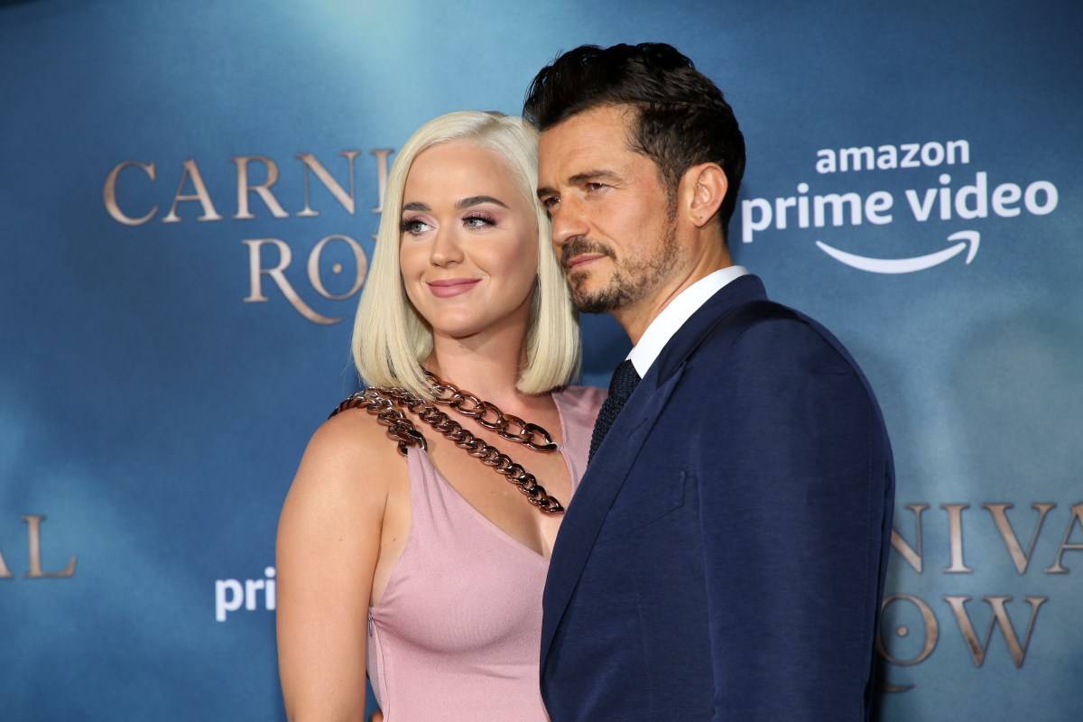 katy perry and orlando bloom pose together against a blue background