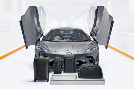 Four new TUMI bags with a McLaren supercar behind them