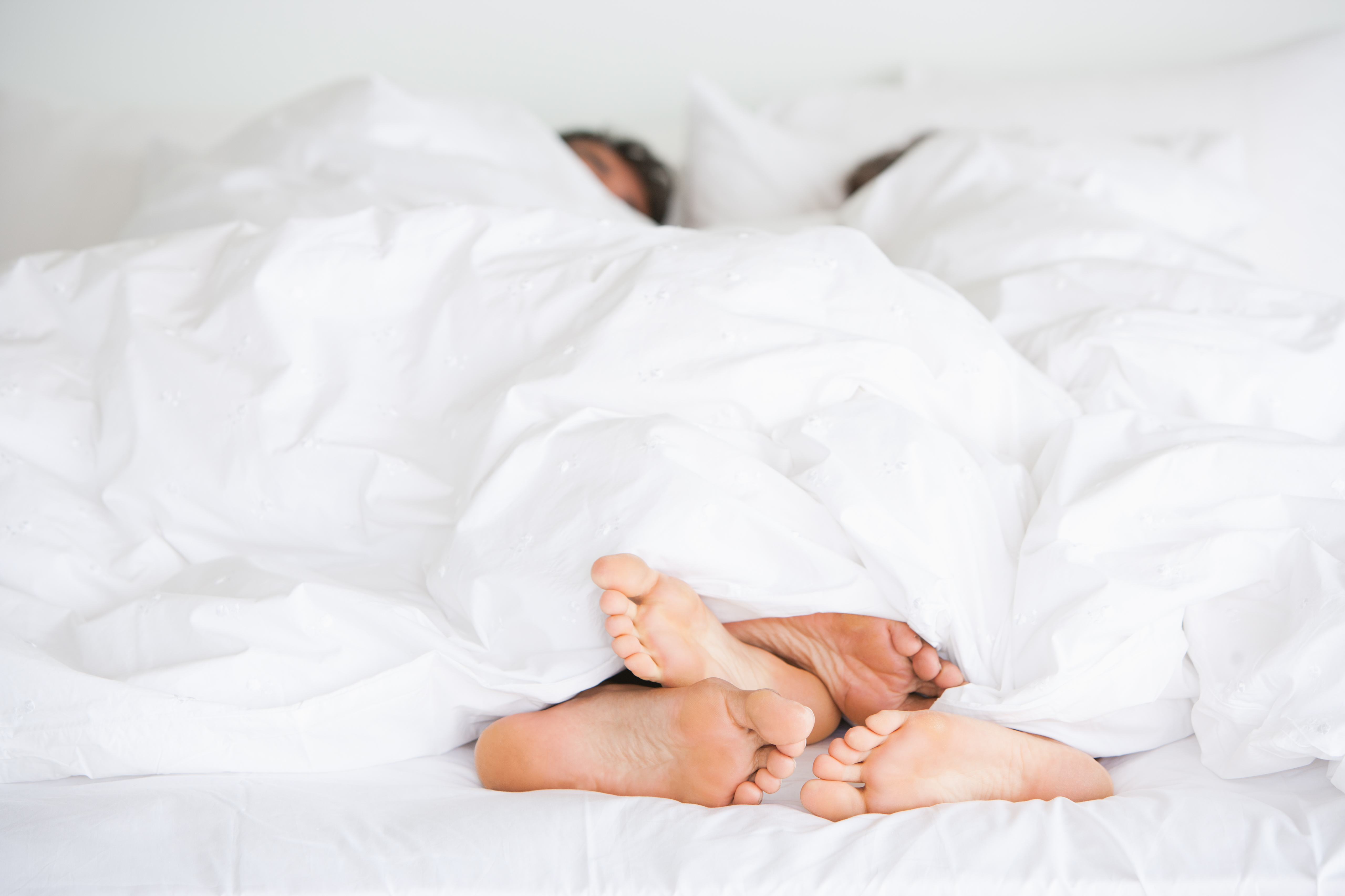 couple's feet in white bed