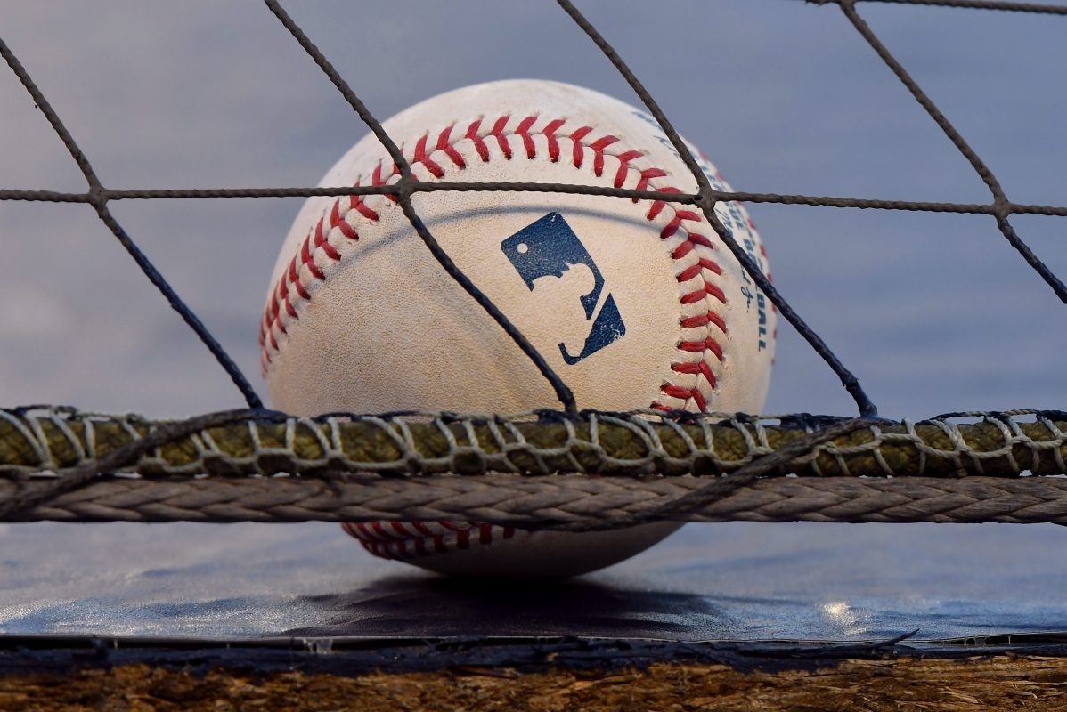 An official Rawlings Major League Baseball sitting on the ground behind a net.