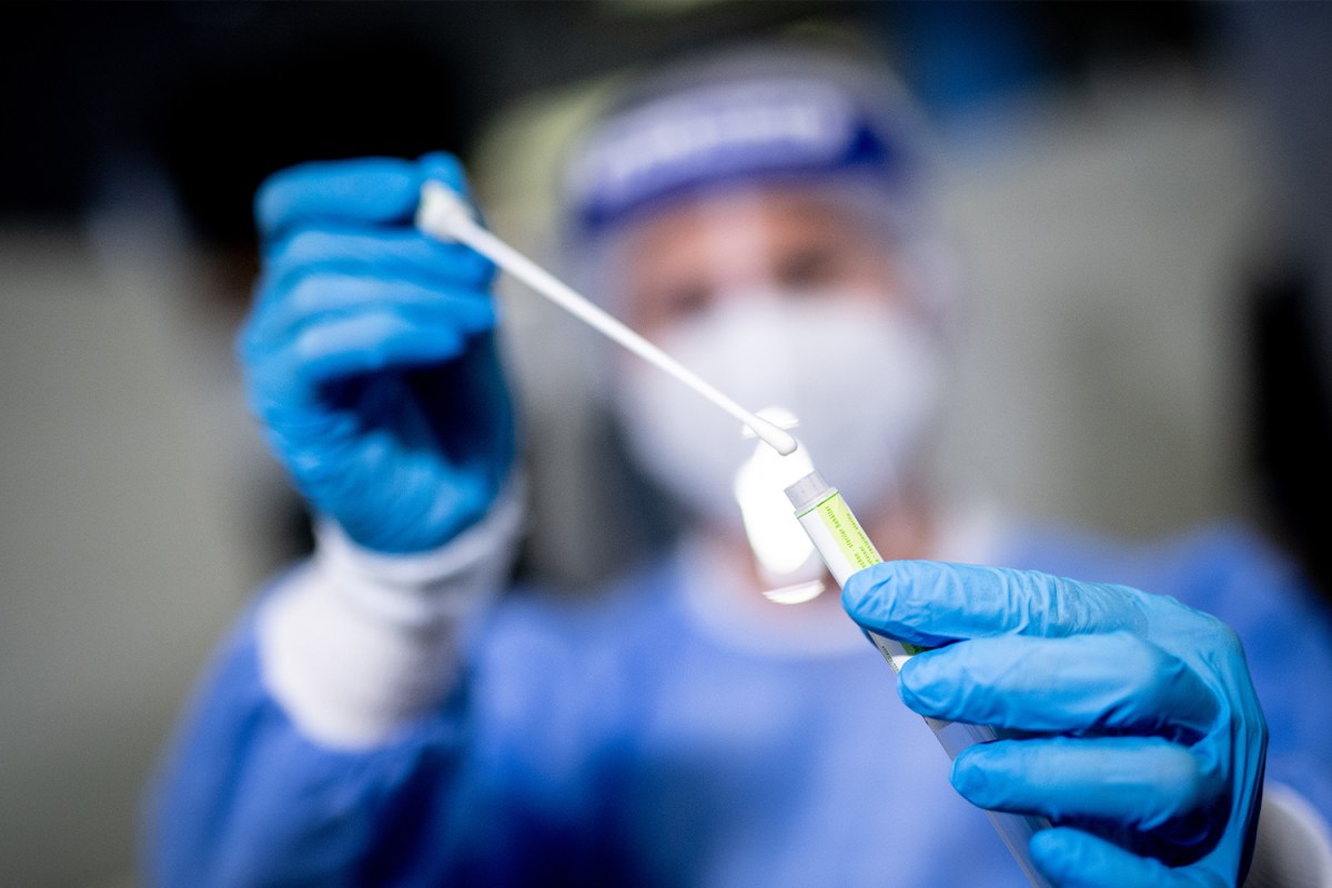 A woman holds the sample from a throat swab in a Covid-19 test center at Munich Airport.