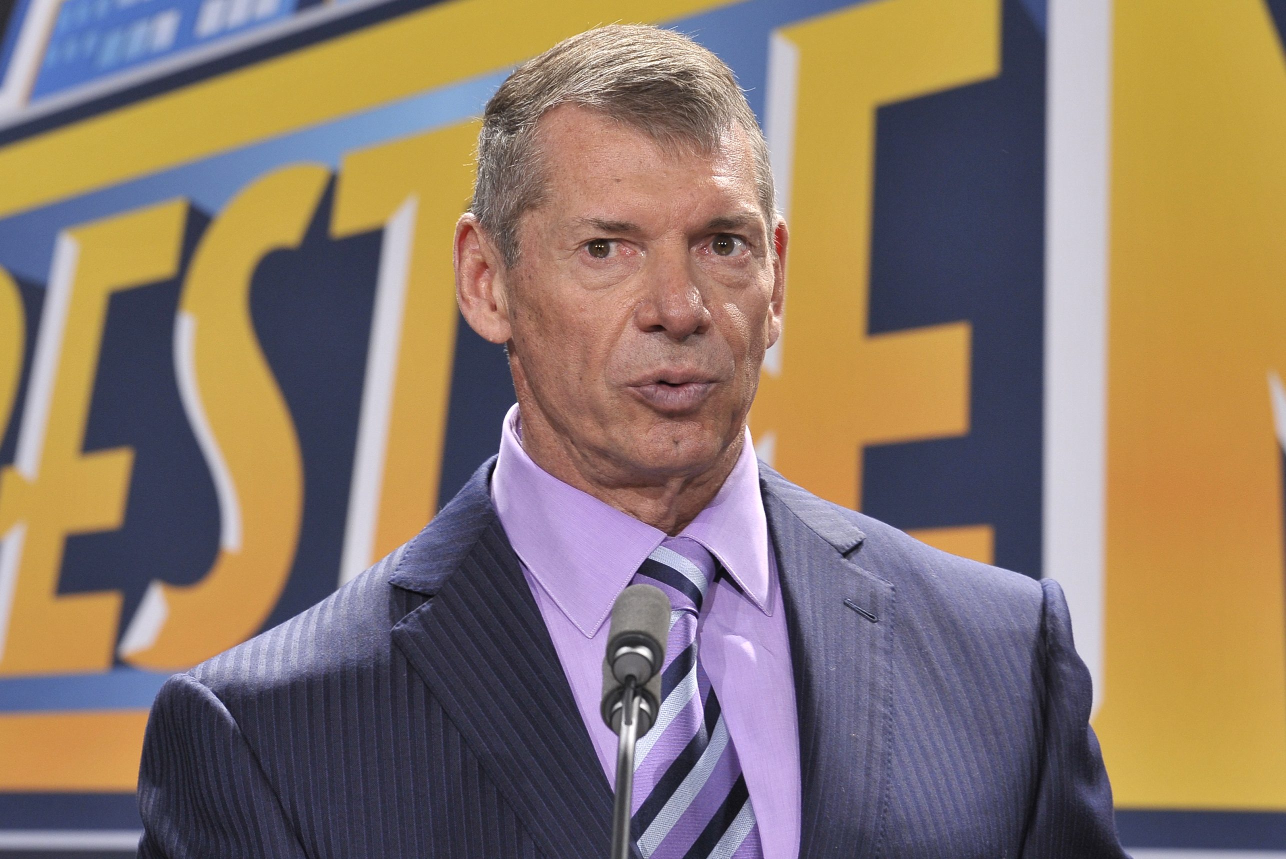 WWE CEO Vince McMahon in a suit with a purple shirt and striped tie