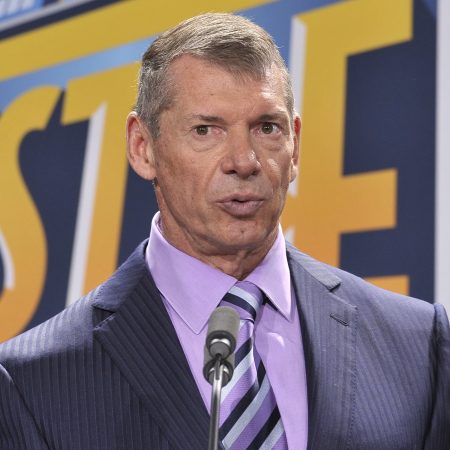 WWE CEO Vince McMahon in a suit with a purple shirt and striped tie