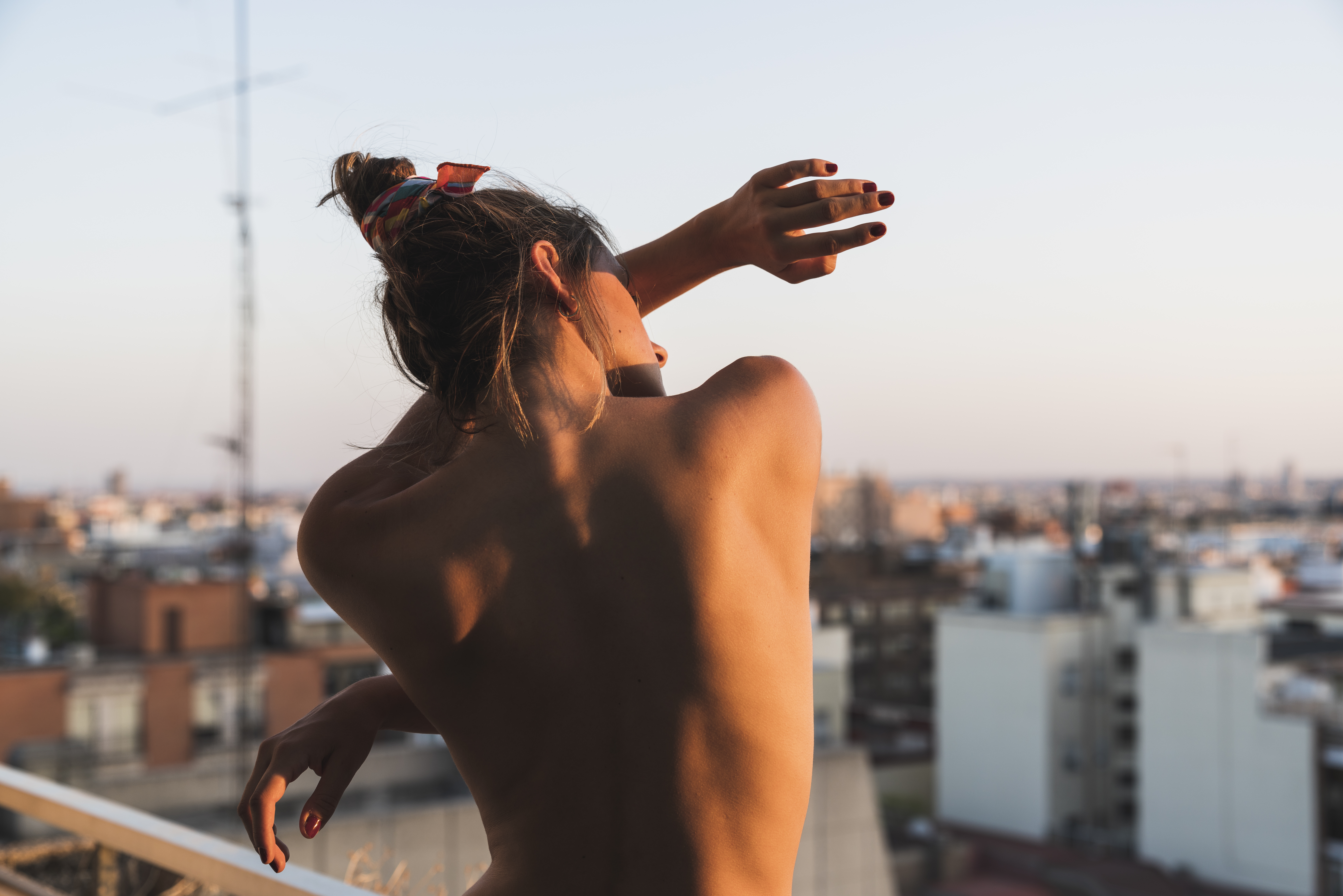 Rear view of topless young woman standing on balcony