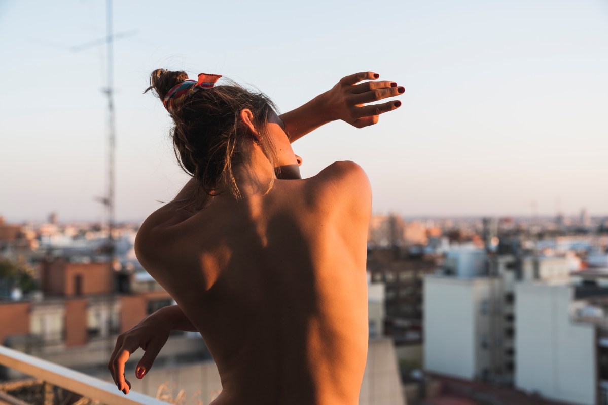 Rear view of topless young woman standing on balcony