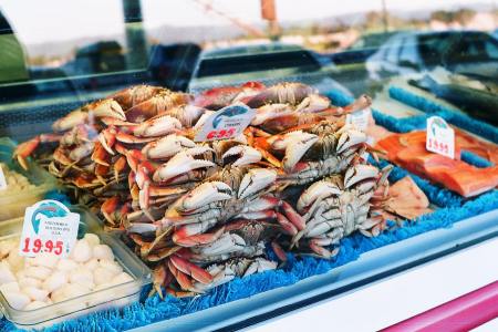 A pile of crabs sitting behind glass at a seafood market