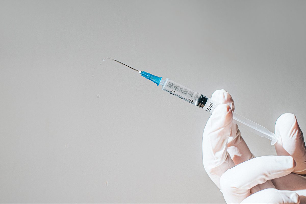 Conceptual image of a gloved hand holding a syringe.