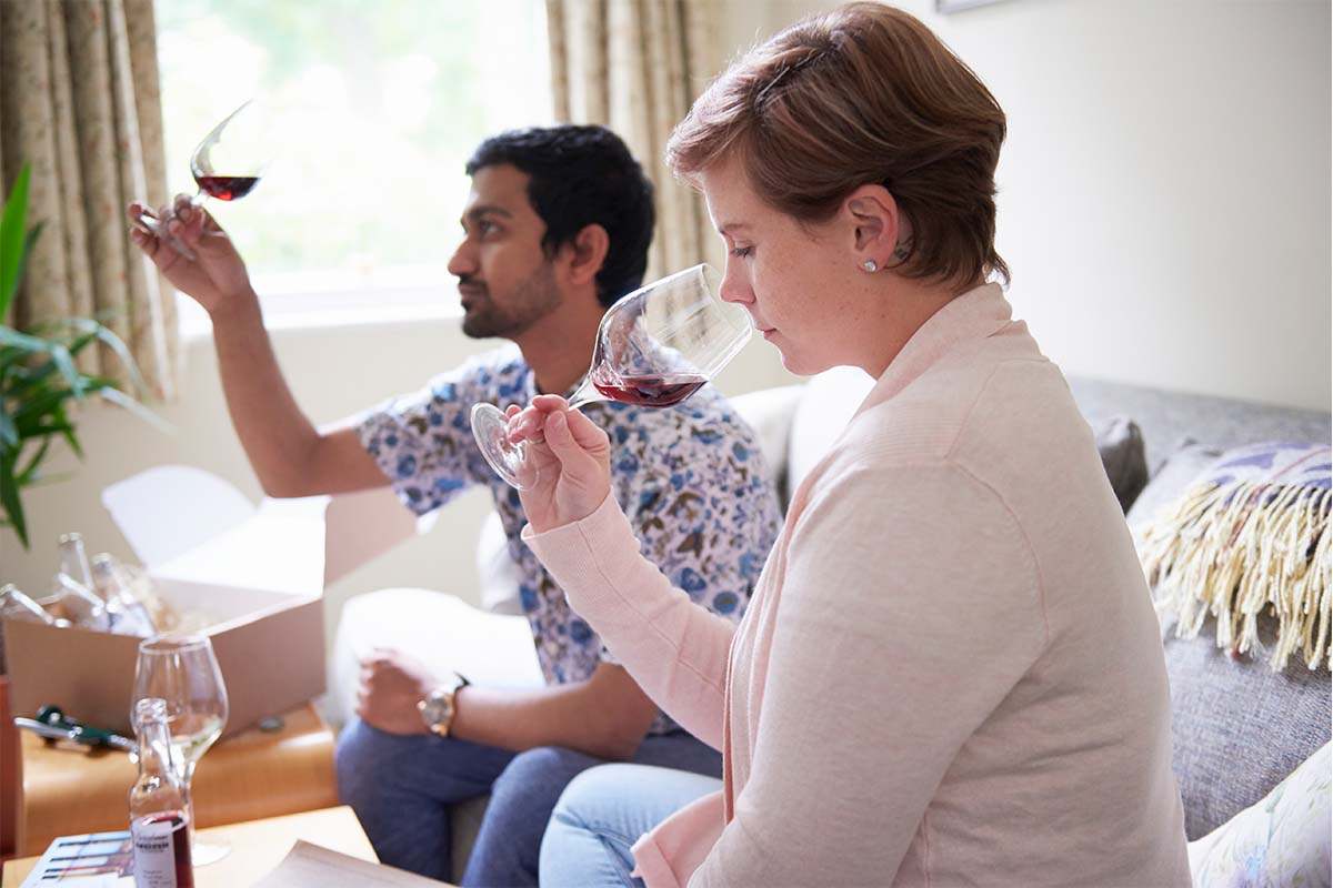 A stock image of man and woman doing wine tasting at home