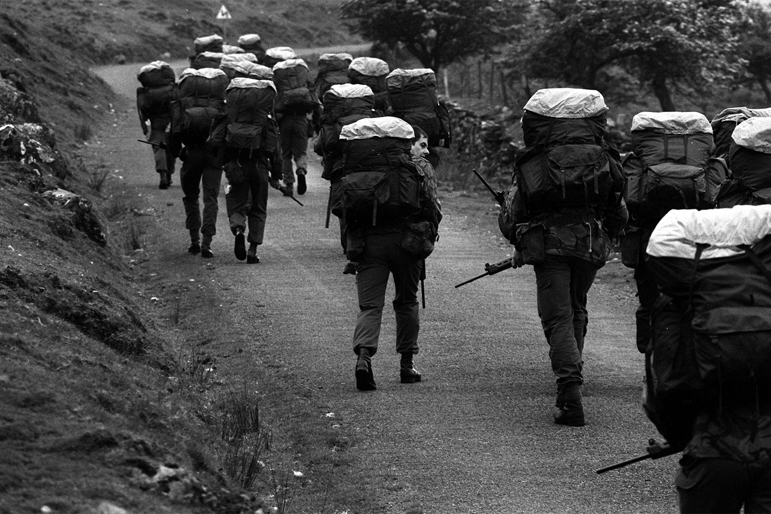 Recruits with 45 lb backpacks and 10 lb FN rifles walk to the top of a mountain before the official start of an endurance march across country because the track is too steep for an Army truck. Allegedly, a recruit who ate a 1lb chocolate bar, making his pack lighter, was made to carry a 2 lb rock instead.