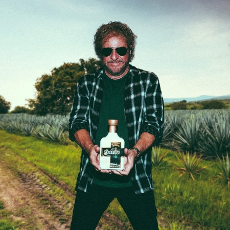 A composite image of Sammy Hagar with a bottle of this Santo tequila, superimposed on an agave field