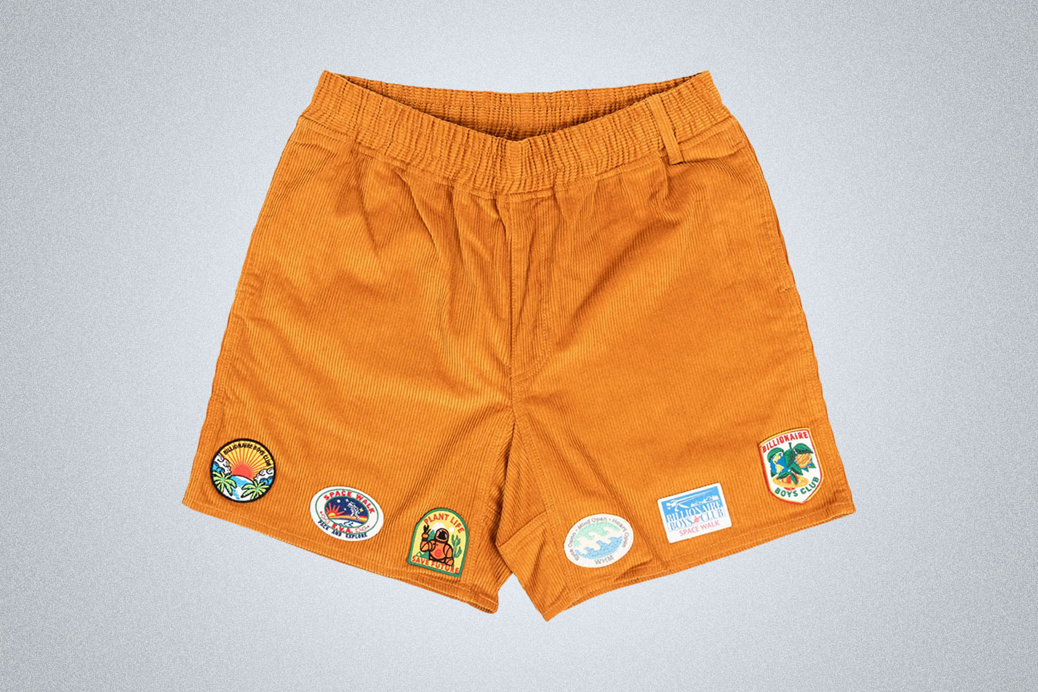 a pair of BBC patched orange corduroy shorts on a grey background