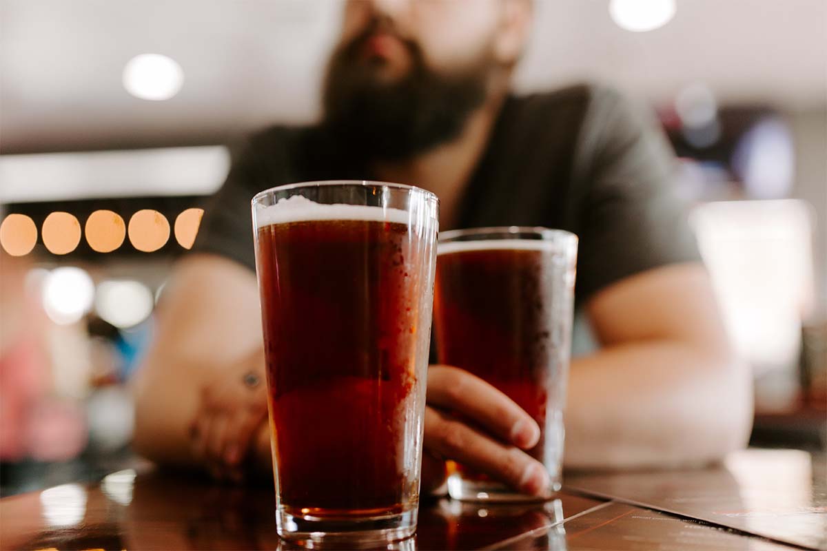 A man drinking two pints of beer. The craft beer industry showed a surprising resilience in 2020, with a net gain of craft breweries.