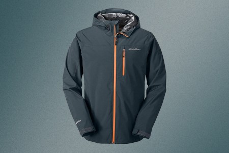 The Eddie Bauer men's Cloud Cap Stretch 2.0 Rain Jacket on a blue background