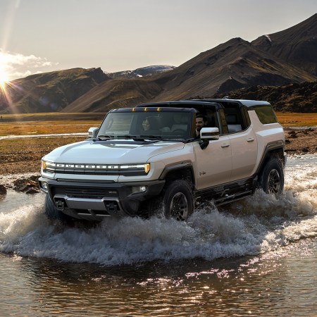 The 2024 GMC Hummer EV SUV fording a stream in the wilderness