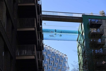 Models swim in a transparent acrylic swimming pool bridge that is fixed between two apartment blocks at Embassy Gardens next to the new US Embassy in south-west London on April 22, 2021. - A world first, the transparent 25-metre-long outdoor pool, known as the Sky Pool, will allow residents to swim from one building to the other, 10 storeys above the ground.