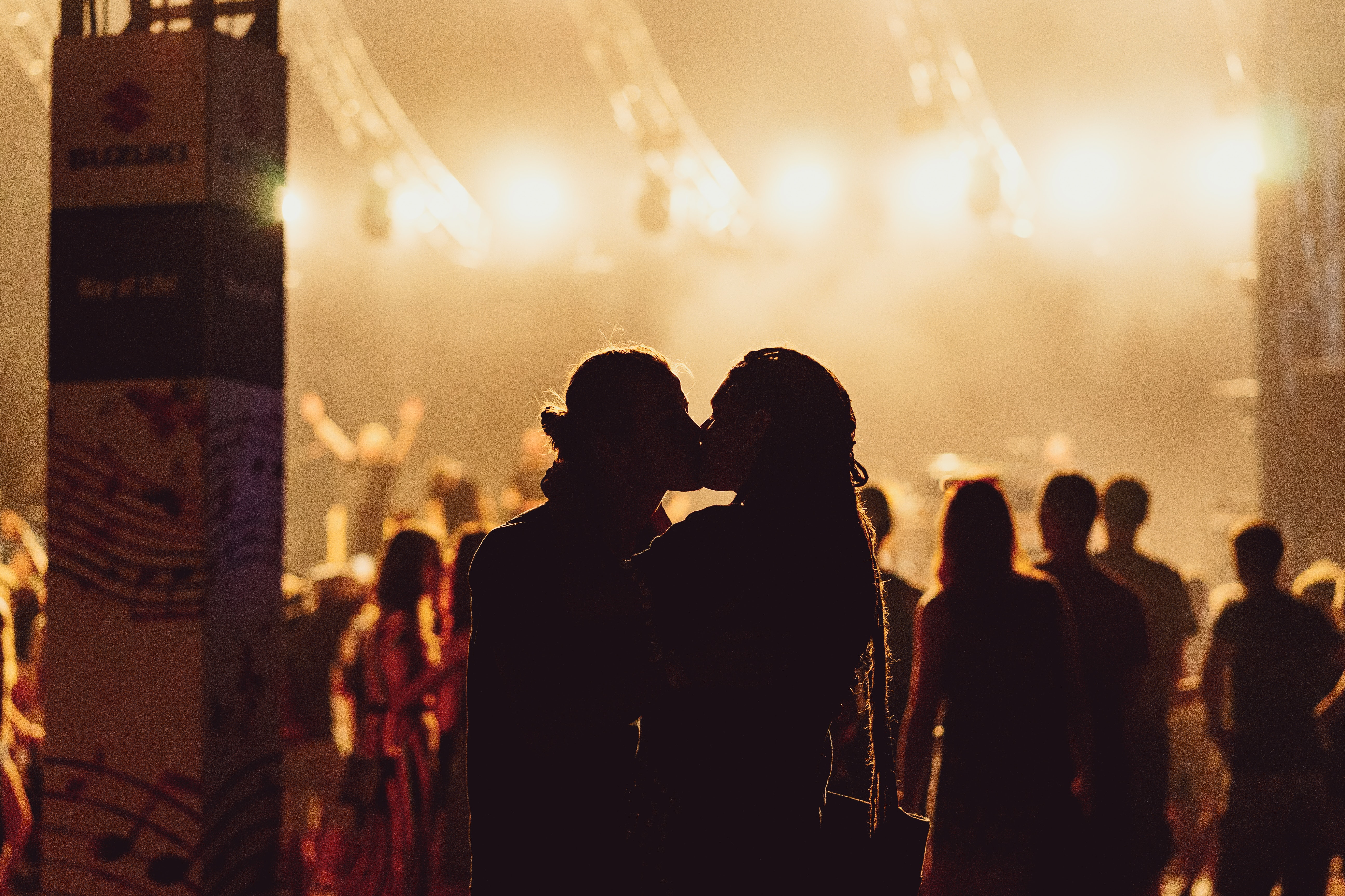Shadowy figures of man and woman kissing during a concert