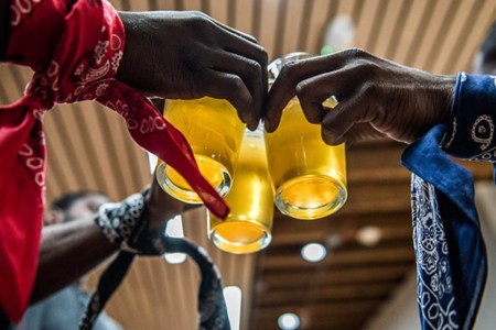 Three glasses of beer held in three hands representing three different gangs. Former gang members work together at TRU Colors in North Carolina.