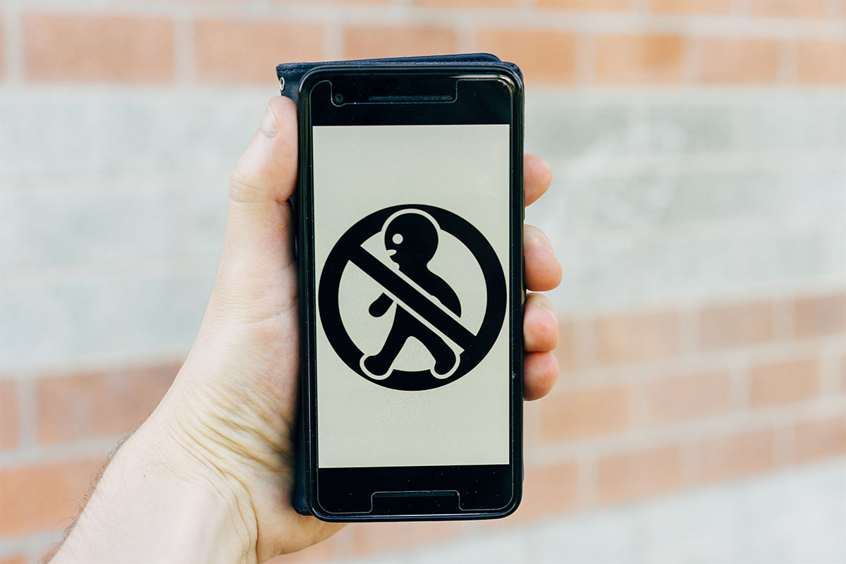 One hand on a phone that is showing a "do not walk" symbol