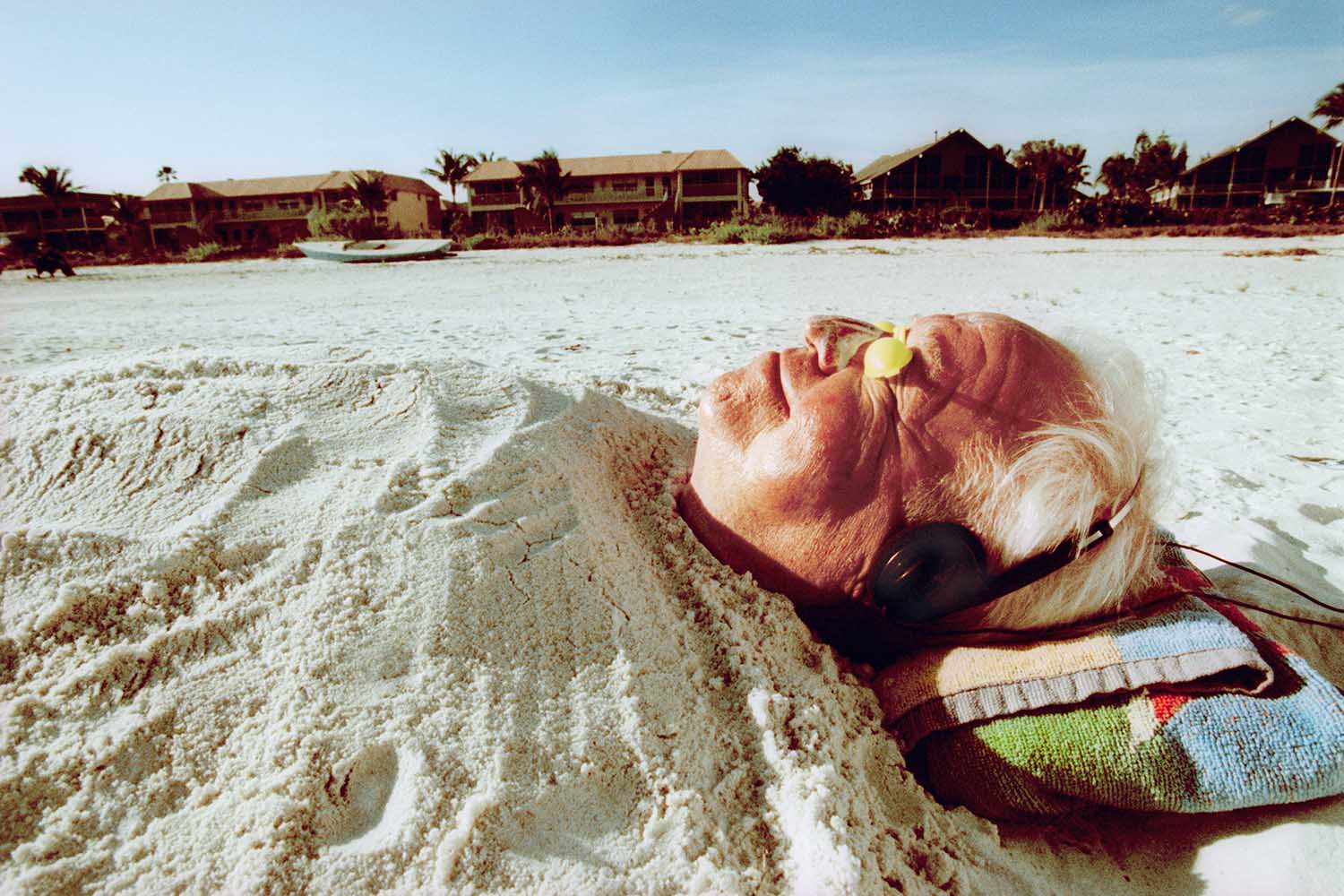 Senior Man Buried in Sand at the Beach - stock photo