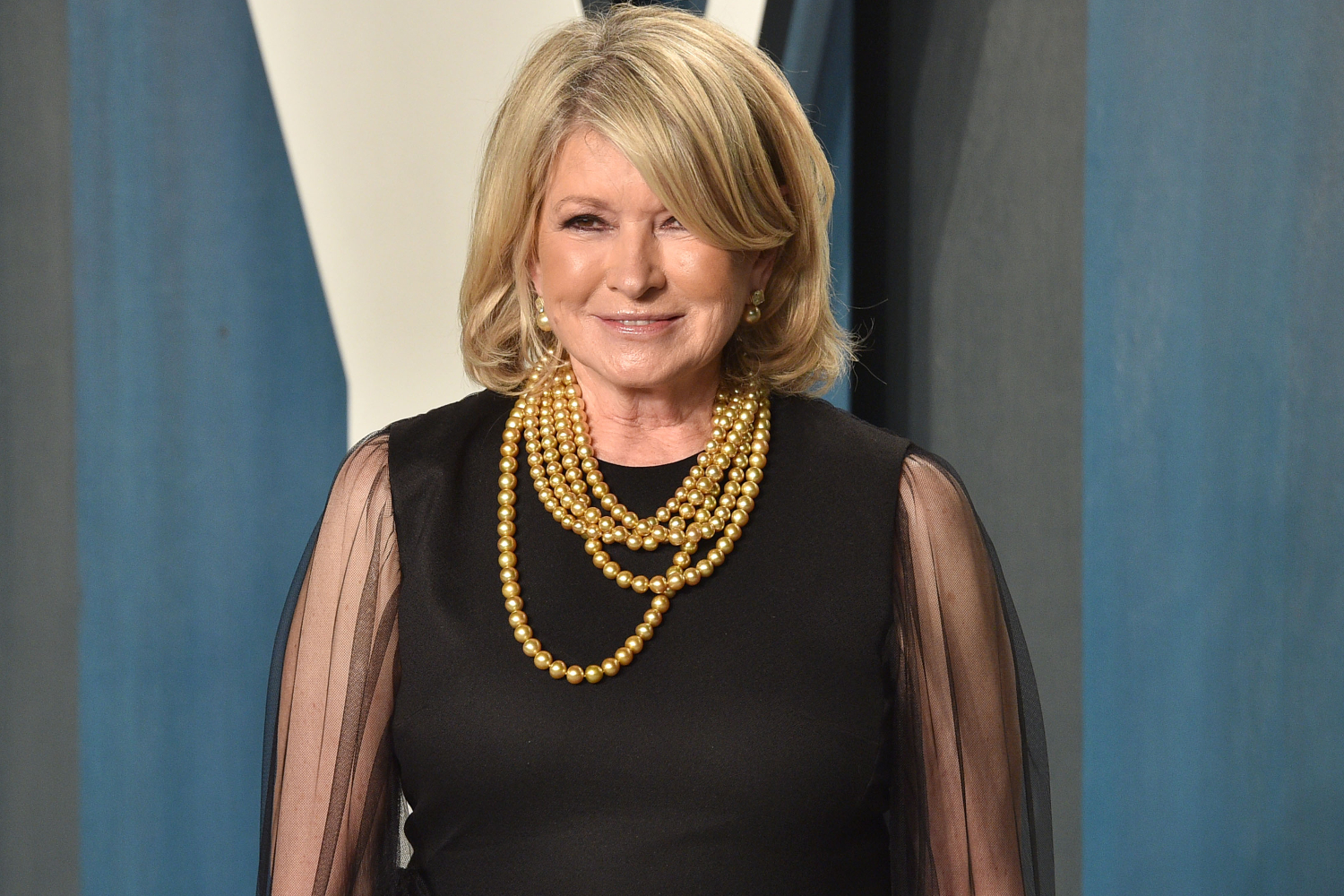 Martha Stewart poses in a black dress and gold necklace