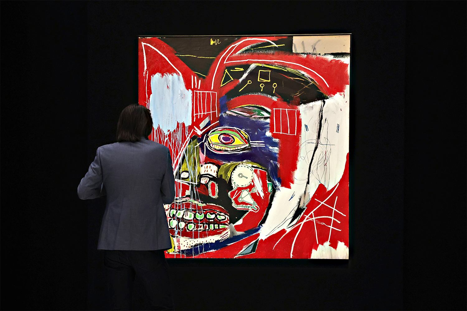 A person standing in front of “In This Case,” a painting by Jean-Michel Basquiat