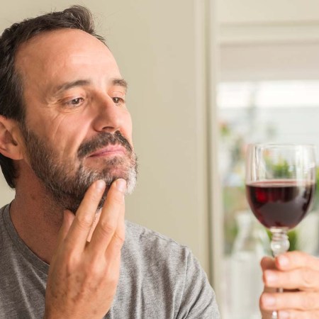 A middle age man drinking a glass of wine serious face thinking about question, very confused idea