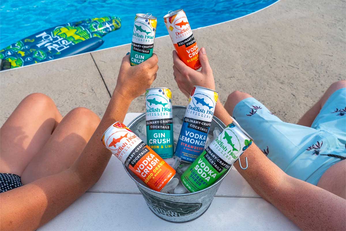 Dogfish Head bucket of Crush cocktails near two people and a pool