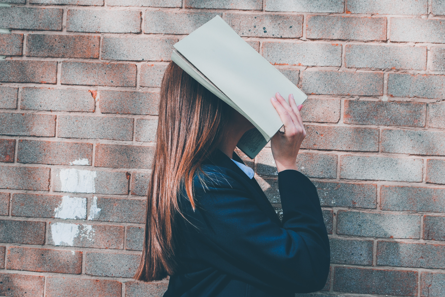 Woman covering her face with an open book