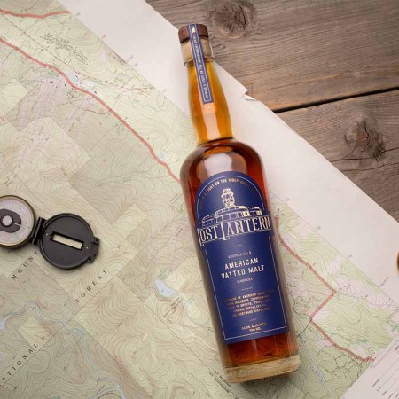 A bottle of Lost Lantern's American Vatted Malt release on a desk with a map