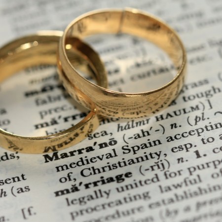 Two gold wedding rings rest on an open dictionary page