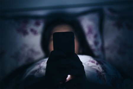 A woman in bed at night with her smartphone. New research suggests "night modes" on phones don't really help with sleep.