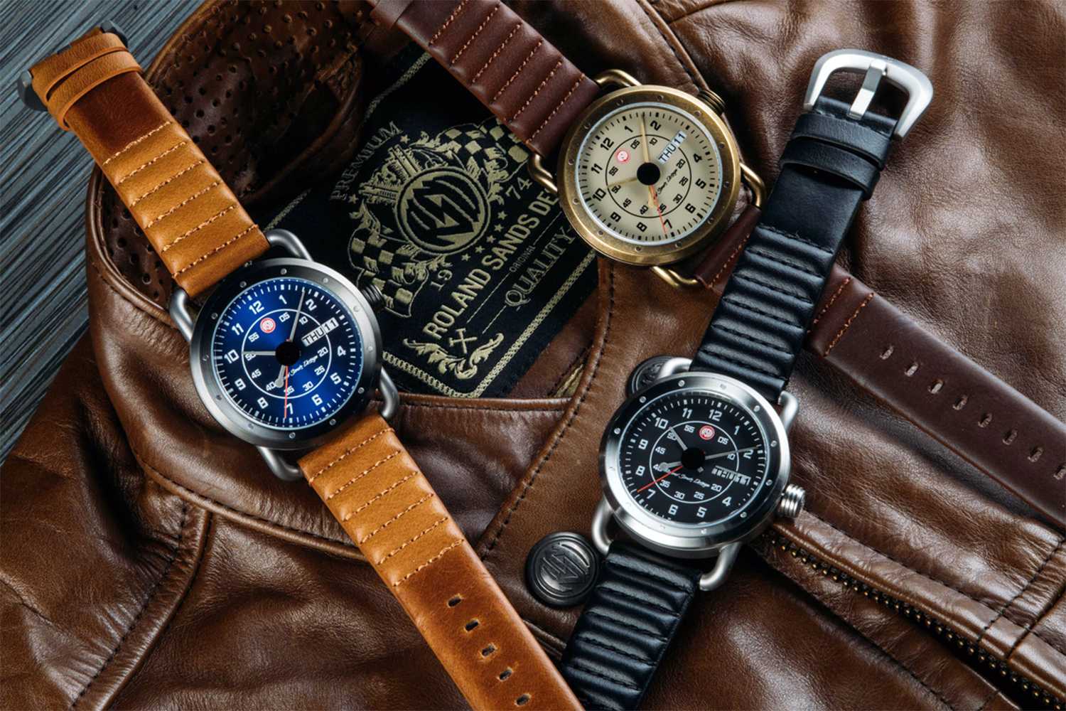 Three watches from Szanto's Roland Sands Icon 2200 Series sitting on top of a brown leather jacket