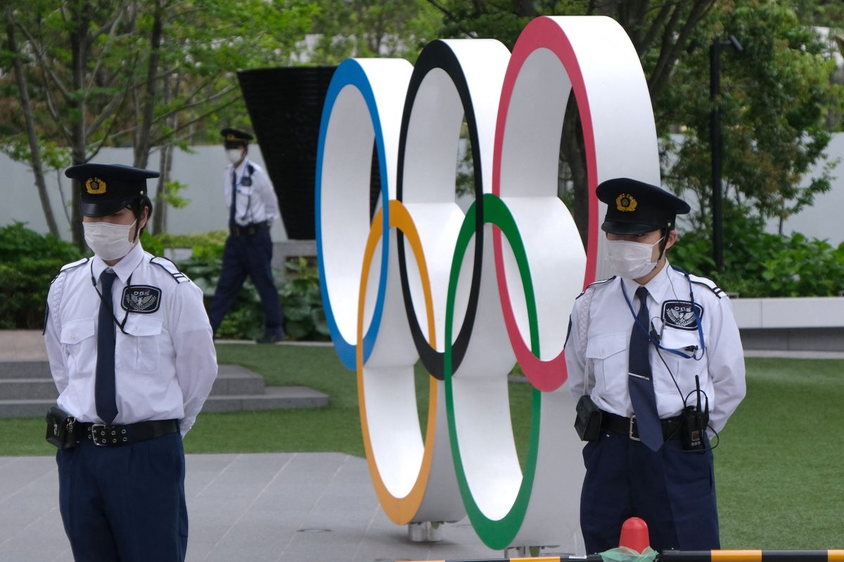 Security guards keep watch next to the Olympic Rings