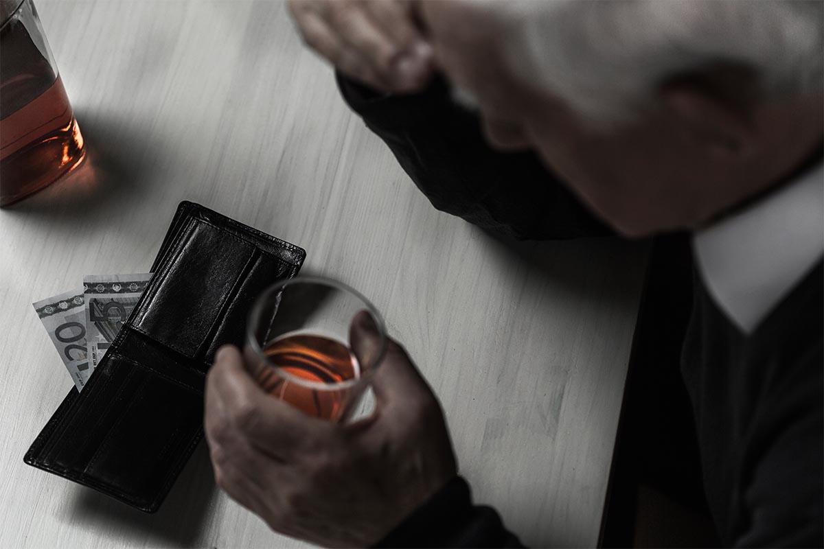 a man drinking whiskey with his wallet open