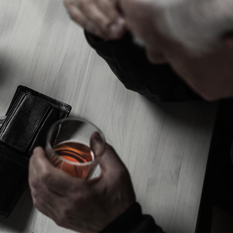 a man drinking whiskey with his wallet open