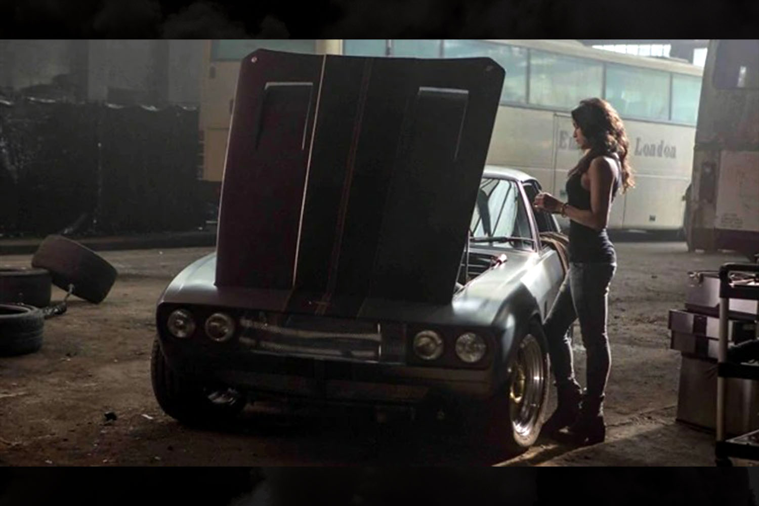 Letty Ortiz (Michelle Rodriguez) standing over a 1971 Jensen Interceptor in a garage in a scene from Fast & Furious 6