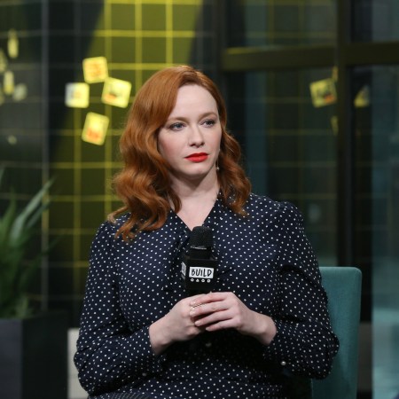 Christina Hendricks holds a microphone on stage, unsmiling