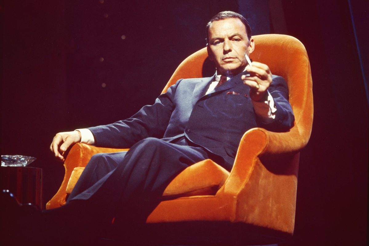 Frank Sinatra sitting in an orange chair in 1955