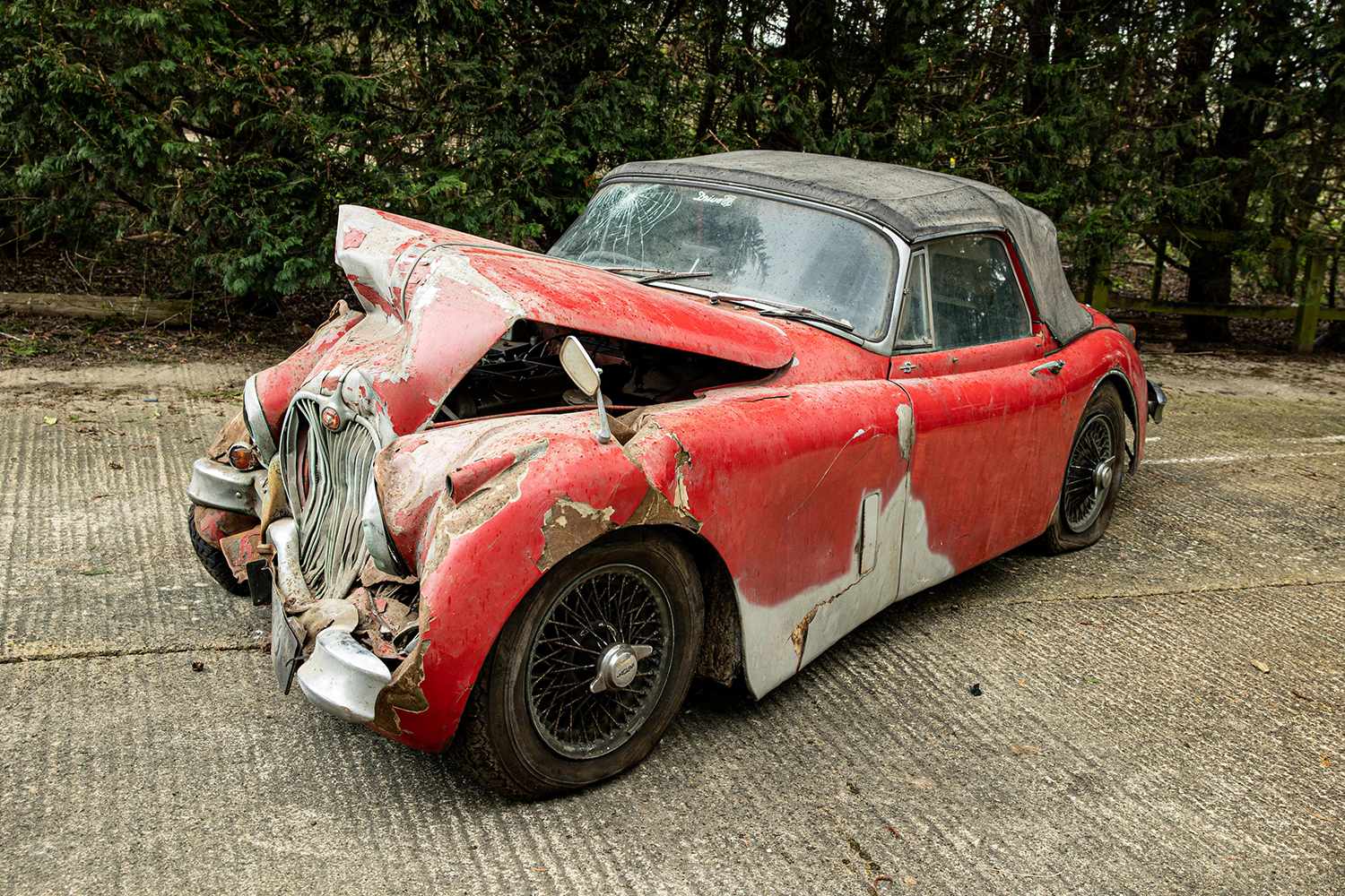A red 1960 Jaguar XK150 that was driven into a tree