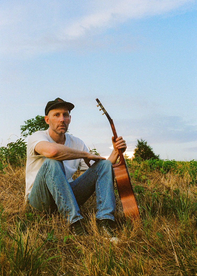 musician matt kearney in a field with a guitar