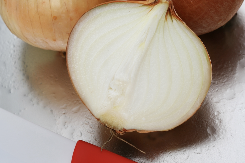 A white onion cut pole-to-pole. Slicing an onion this way makes you cry less compared to orbital sliving.