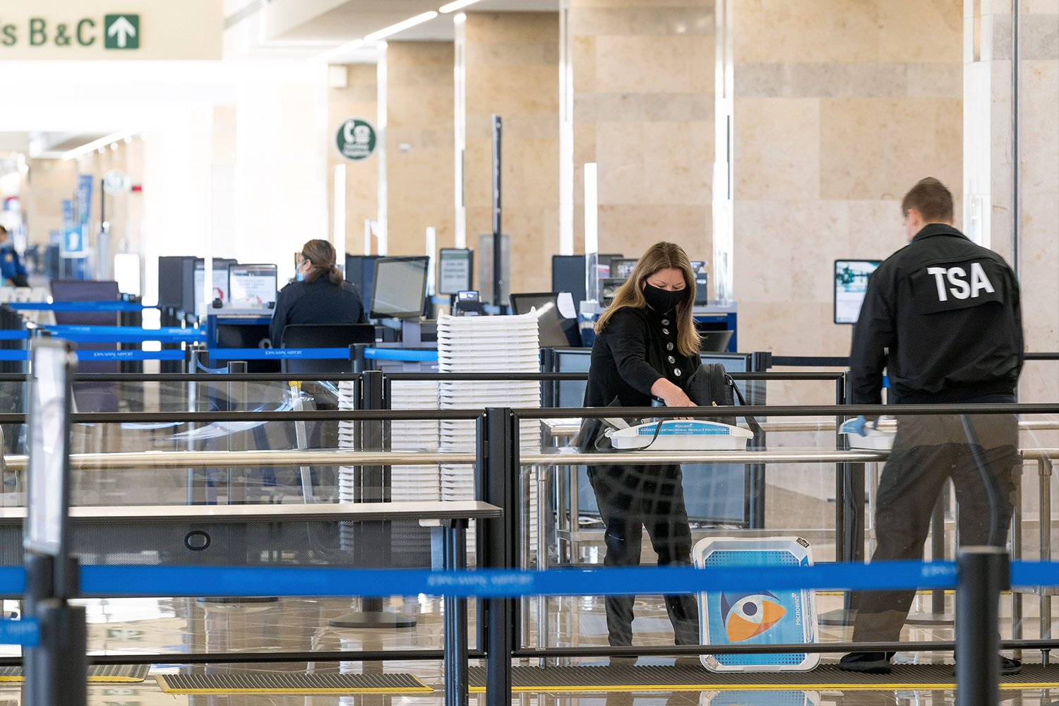 A TSA agent helps a traveler through security checkpoint at John Wayne Airport