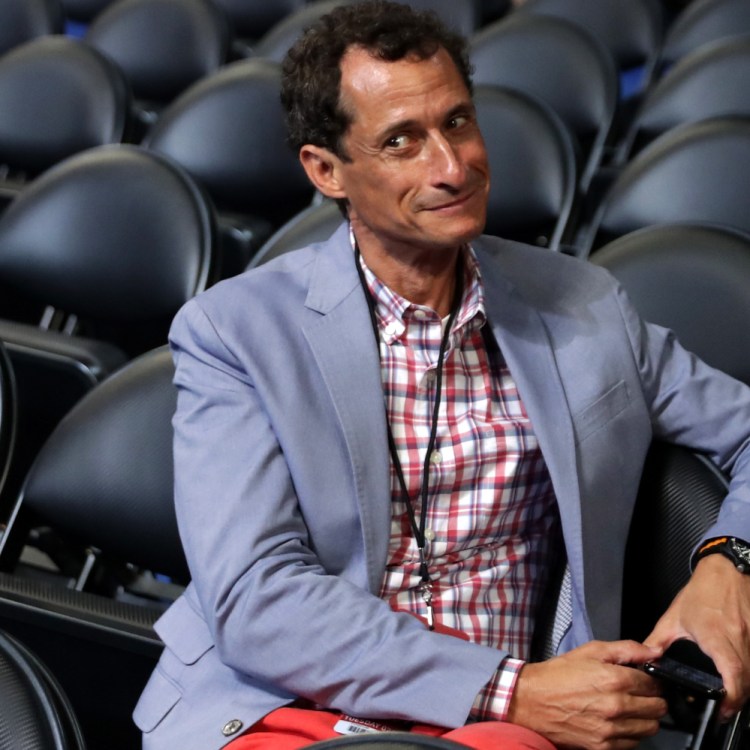 anthony weiner sitting in rows of black folding chairs holding phone