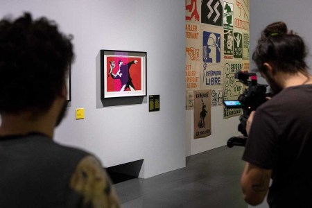 A video maker films Banksy's work "Love is in the Air (Flower Thrower)" during the press preview of the "The Art of BANKSY. A Visual Protest" exhibition at MUDEC on November 20, 2018 in Milan, Italy.