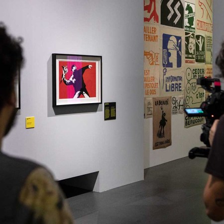 A video maker films Banksy's work "Love is in the Air (Flower Thrower)" during the press preview of the "The Art of BANKSY. A Visual Protest" exhibition at MUDEC on November 20, 2018 in Milan, Italy.