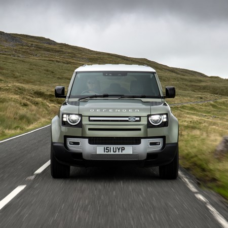 A Land Rover Defender driving down a country road