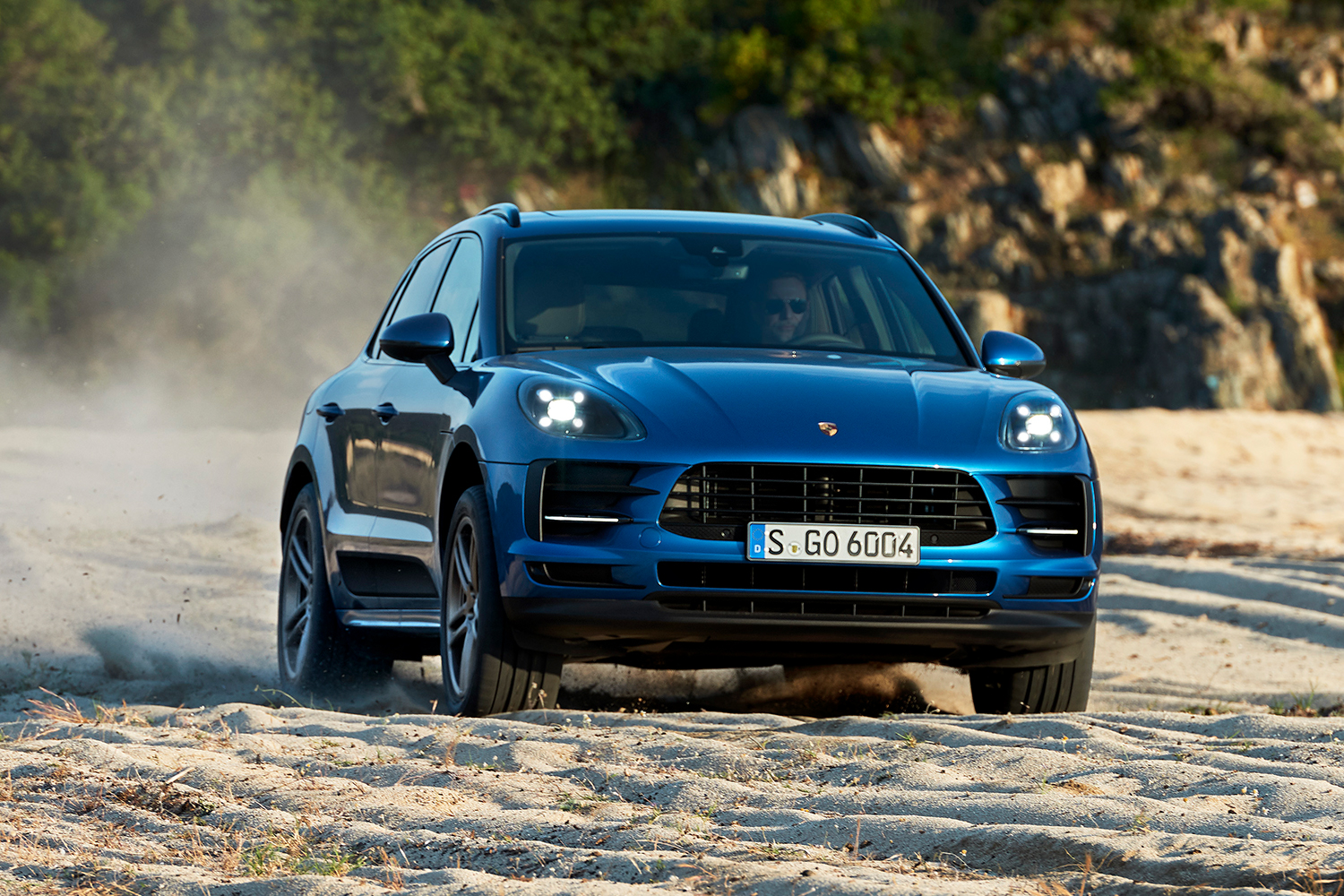 The new Porsche Macan SUV in blue driving on the sand