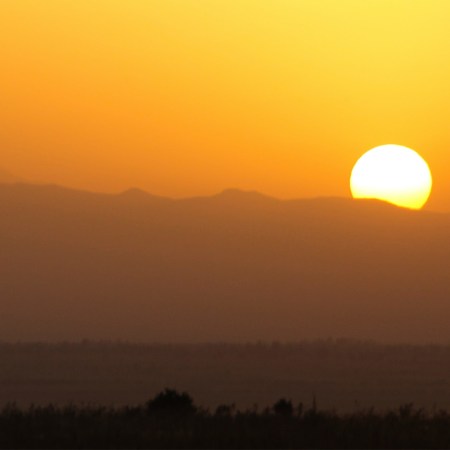 The sun rises over the mountains. In the Pacific Northwest, a heat dome has led to record-breaking temperatures.